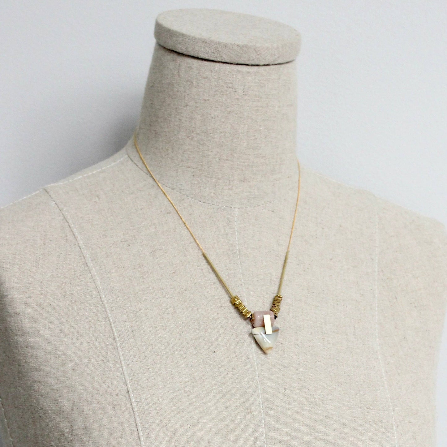Necklace on a mannequin bust against a plain background