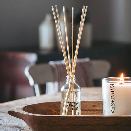 Diffuser with wooden sticks and a candle on a wooden tray with a blurred background