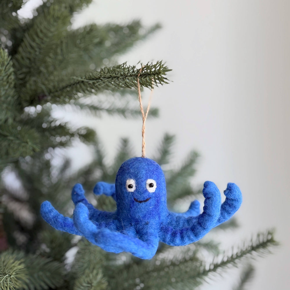 Blue octopus ornament hanging on a Christmas tree branch.
