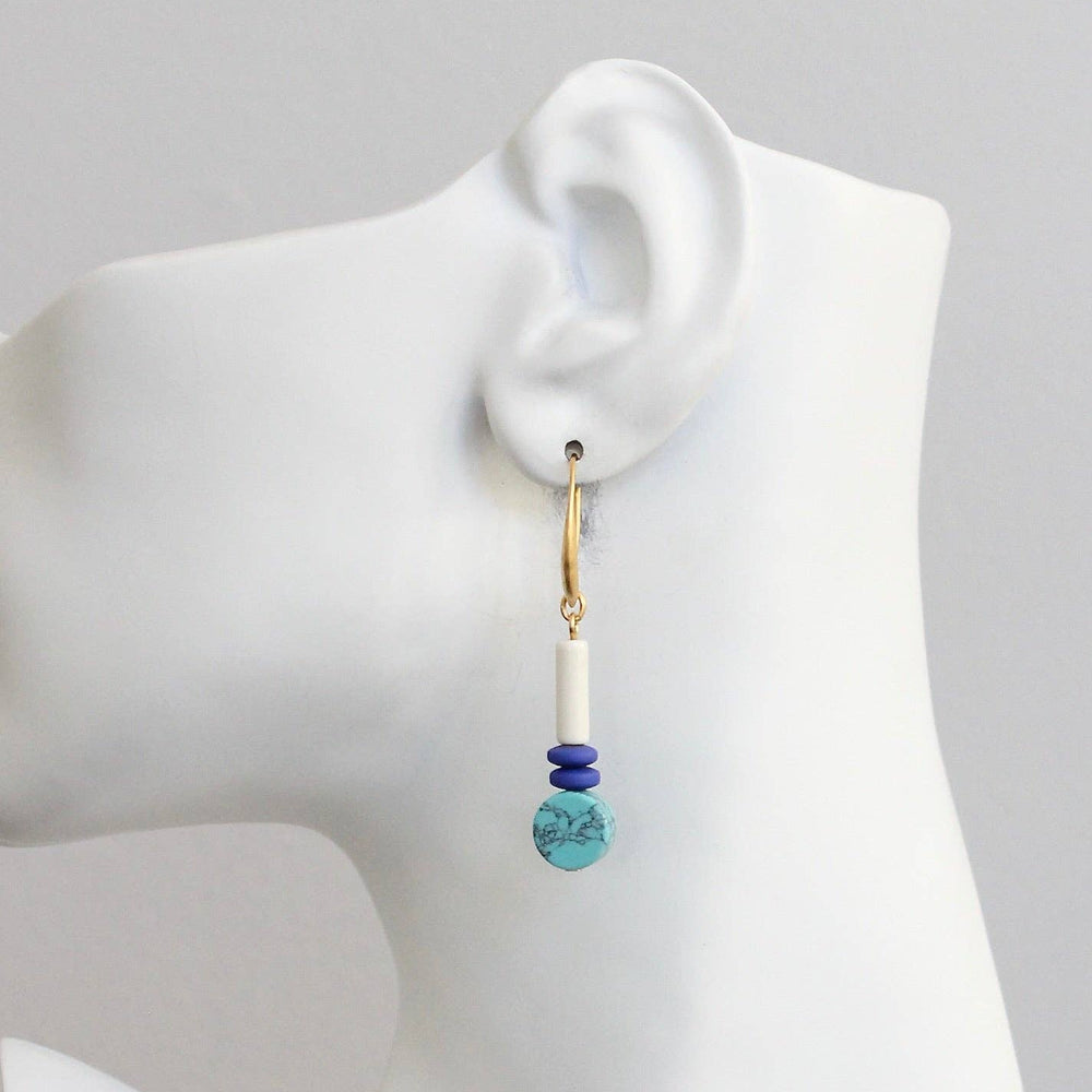 Earring on a mannequin ear with a plain background