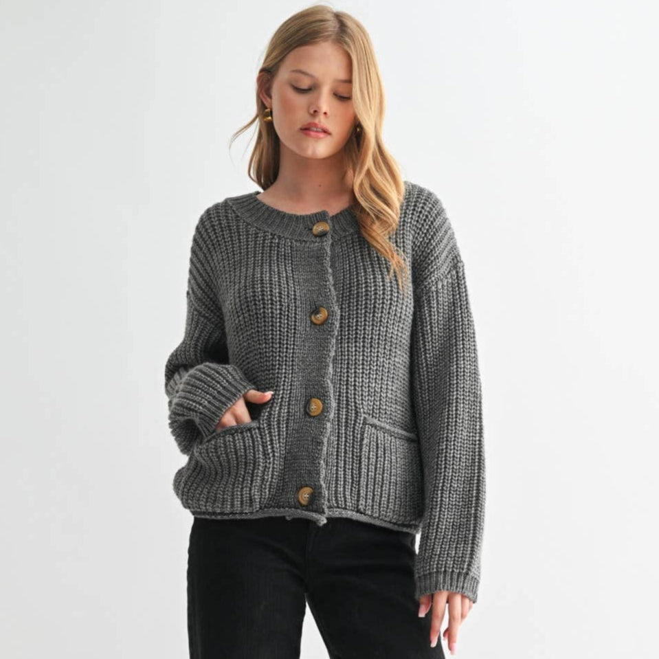 Woman wearing a gray textured cardigan with brown buttons on a white background