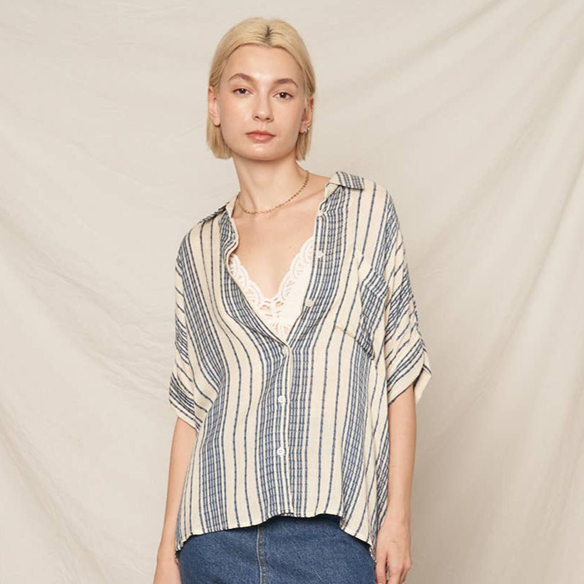 Woman wearing a striped shirt and jeans against a plain background