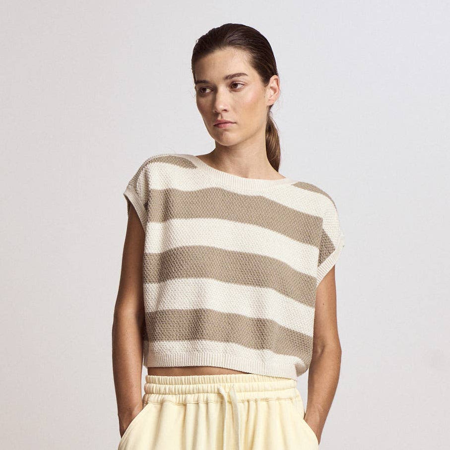Woman wearing a striped top and beige pants on a plain background