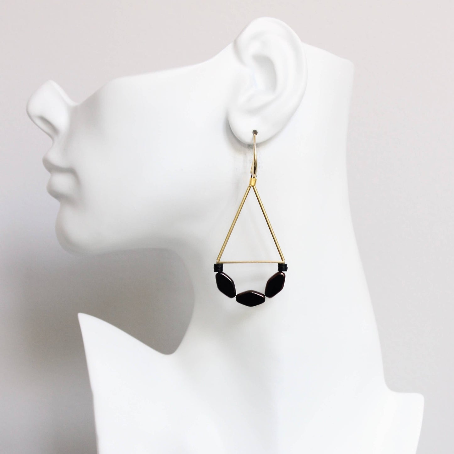Black beaded earring on a white mannequin head against a white background