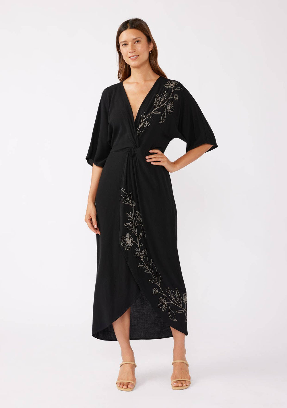 Woman wearing a black kimono-style dress with floral embroidery on a white background