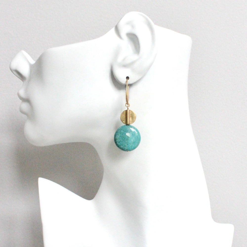 Turquoise earrings on a white mannequin head against a gray background