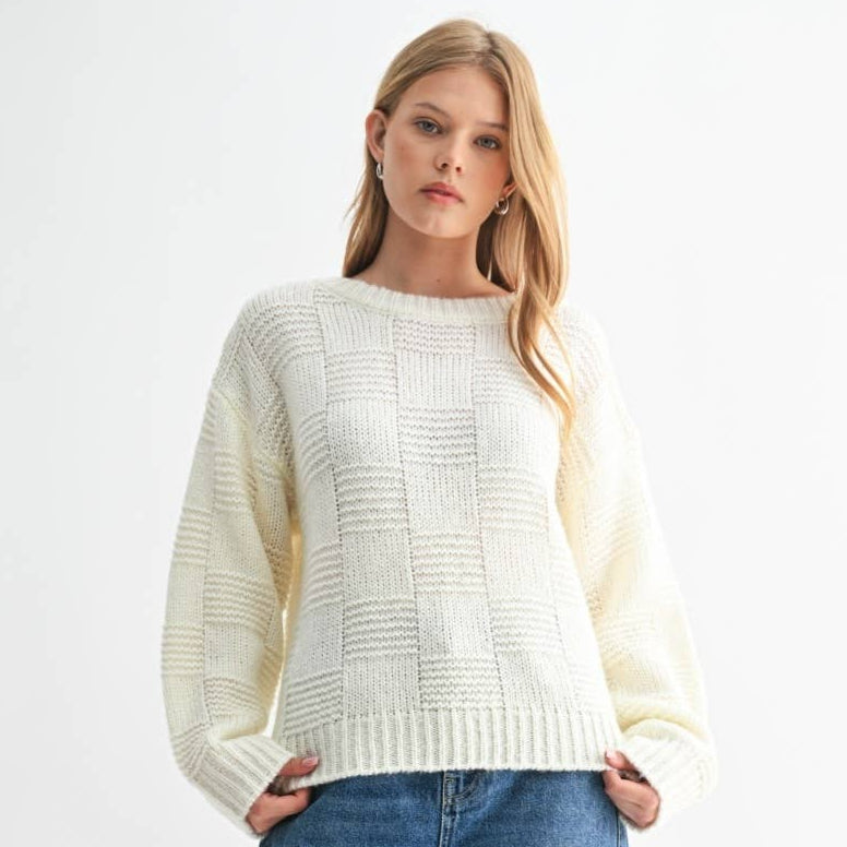 Woman wearing a white sweater and blue jeans on a white background