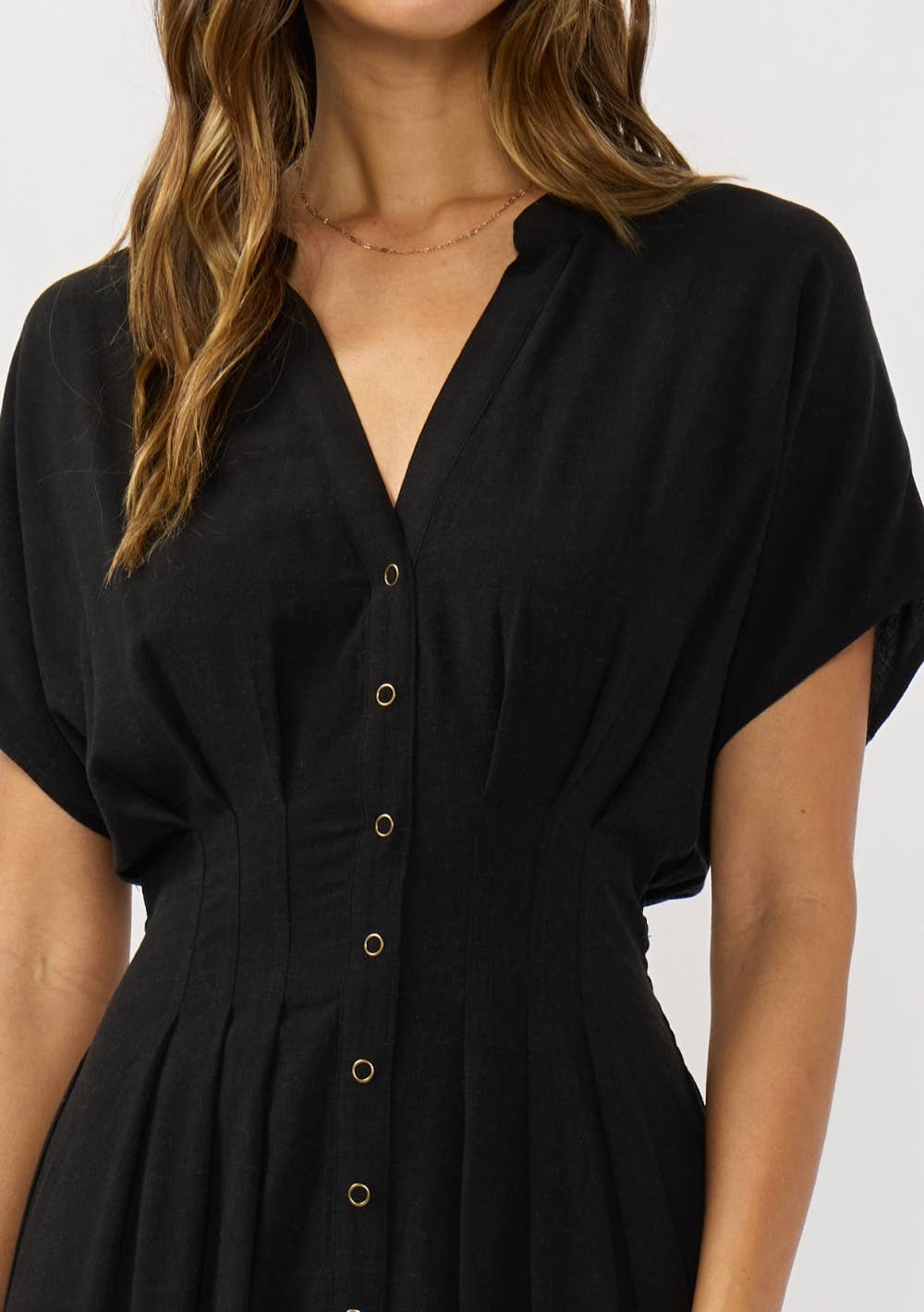Black dress with short sleeves and buttons on a plain background