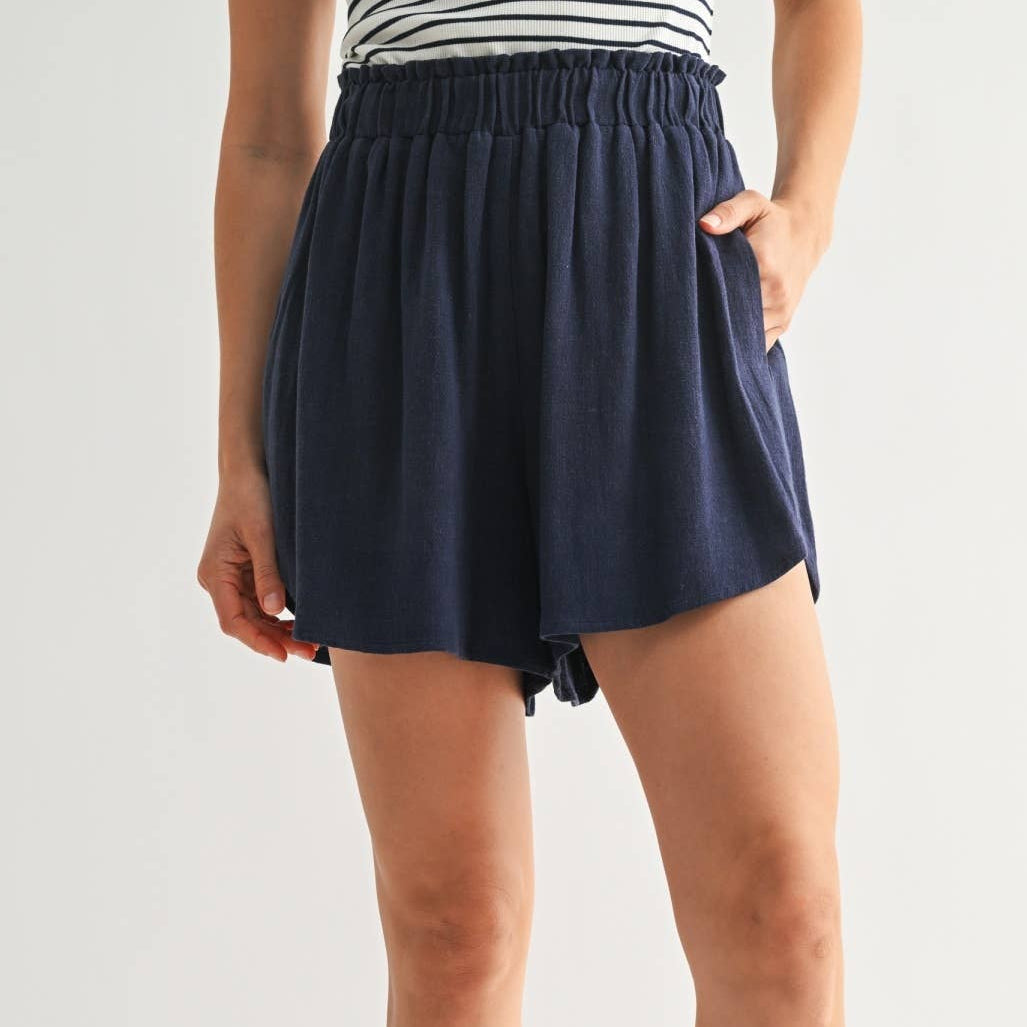 Person wearing navy shorts on a plain background