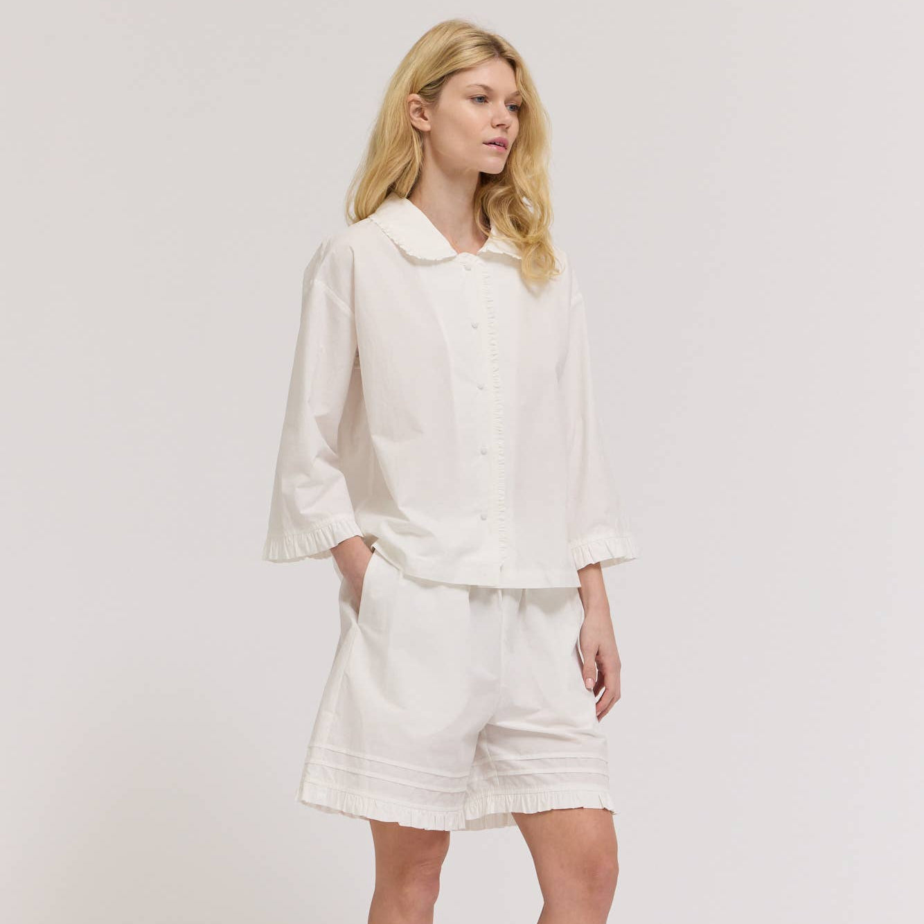 Woman wearing a white outfit with a plain background