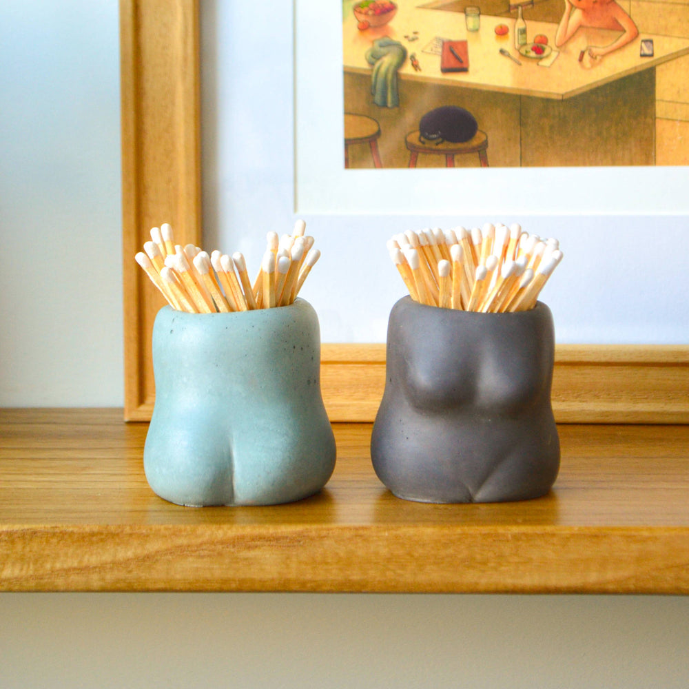 Two ceramic holders with toothpicks on a wooden surface, with a blurred background of a kitchen.