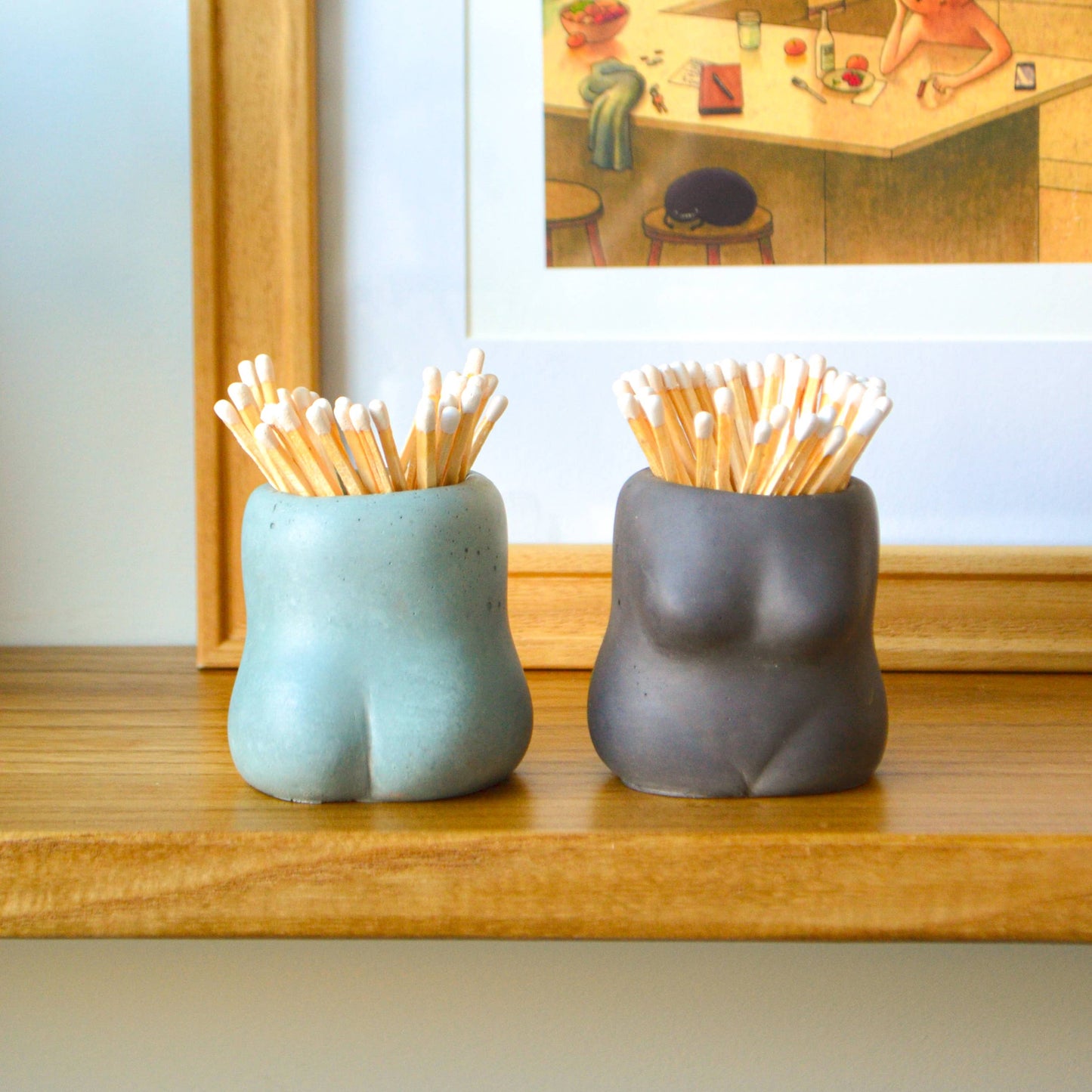 Two ceramic holders with toothpicks on a wooden surface, with a blurred background of a kitchen.