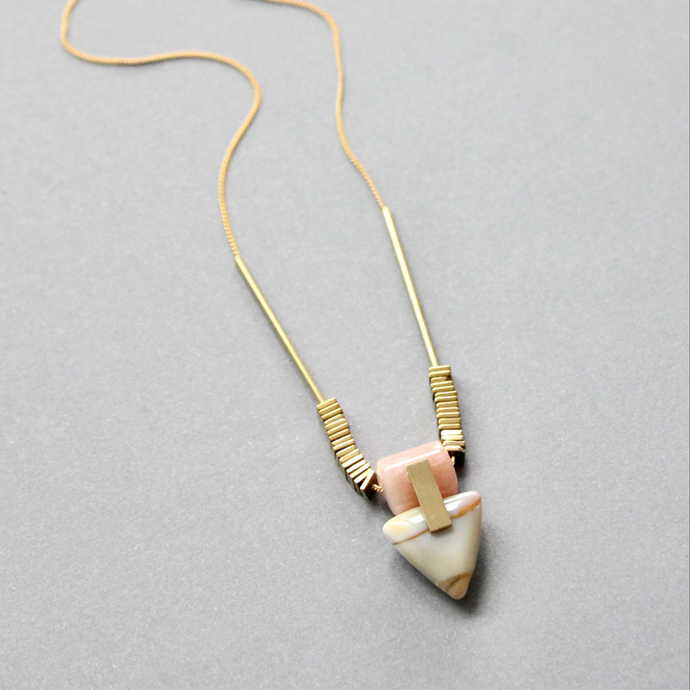 Necklace with a gold chain and stone pendant on a gray background