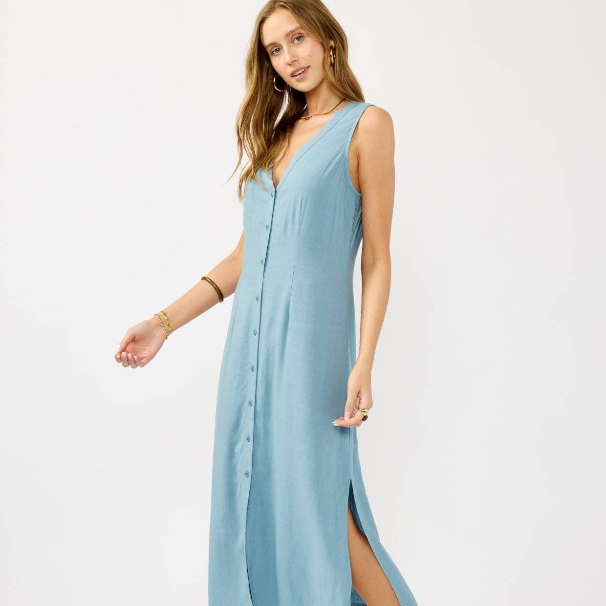 Woman wearing a light blue sleeveless dress with a slit on a white background