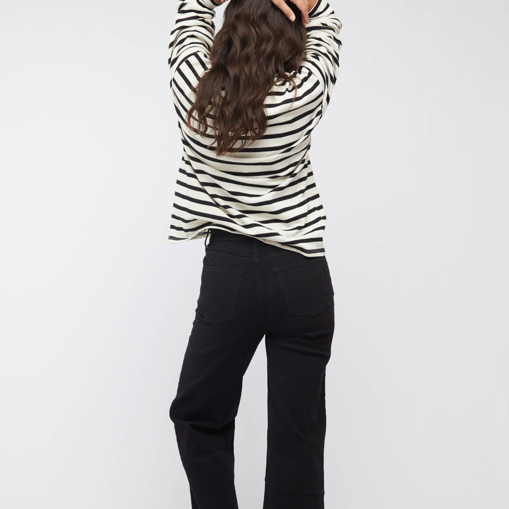 Person wearing a black and white striped shirt and black pants on a white background