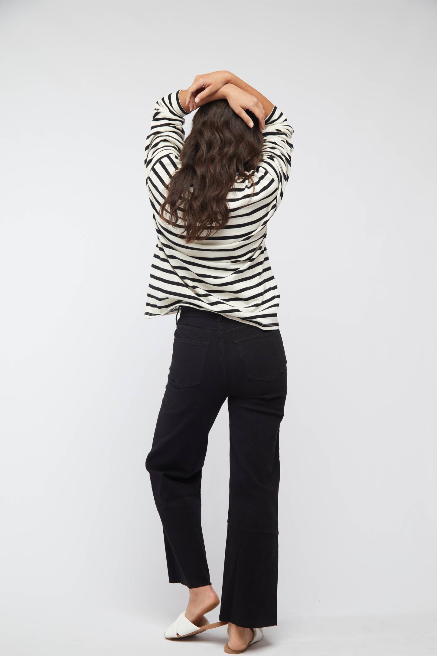 Person wearing a black and white striped shirt and black pants on a white background