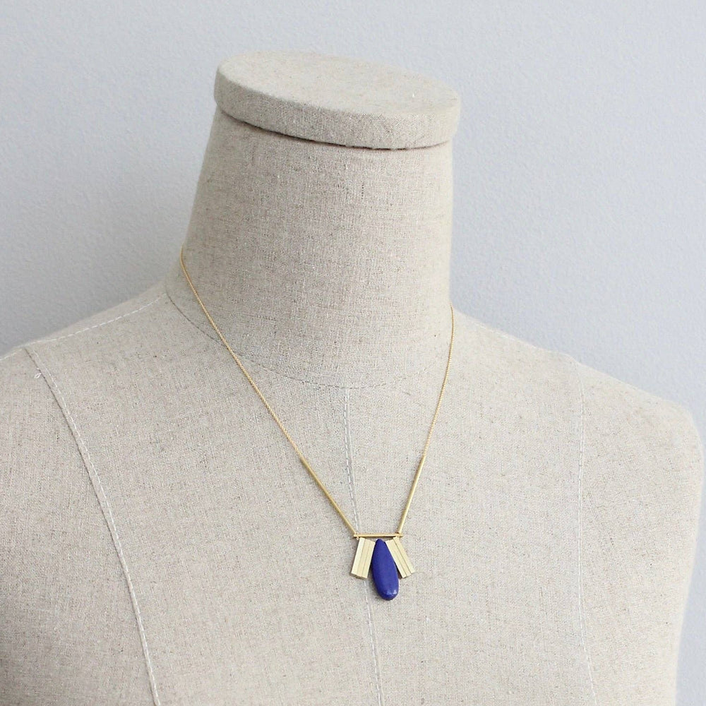 Necklace with a blue pendant on a mannequin against a plain background