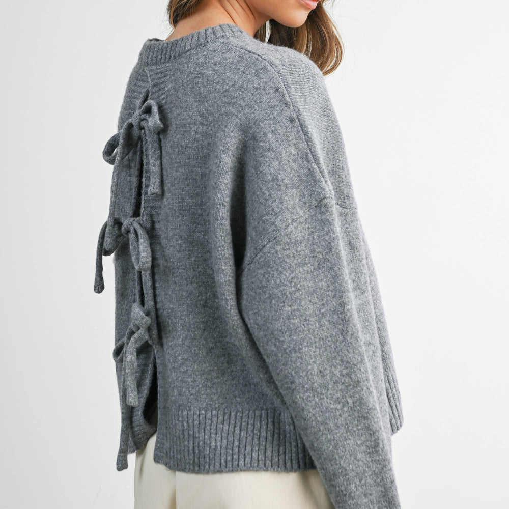 Woman wearing a gray sweater with lace-up details on a white background