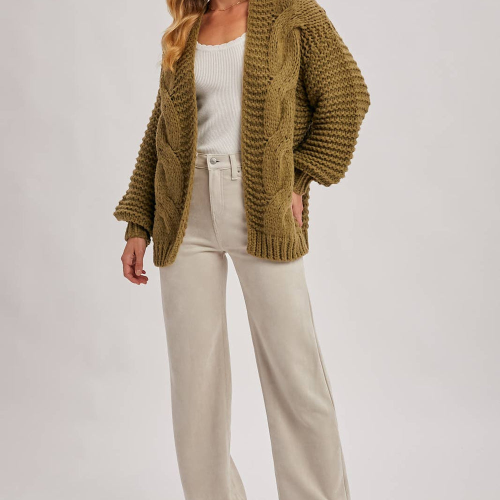 
                      
                        Woman wearing a green cardigan, white top, and beige pants on a white background
                      
                    