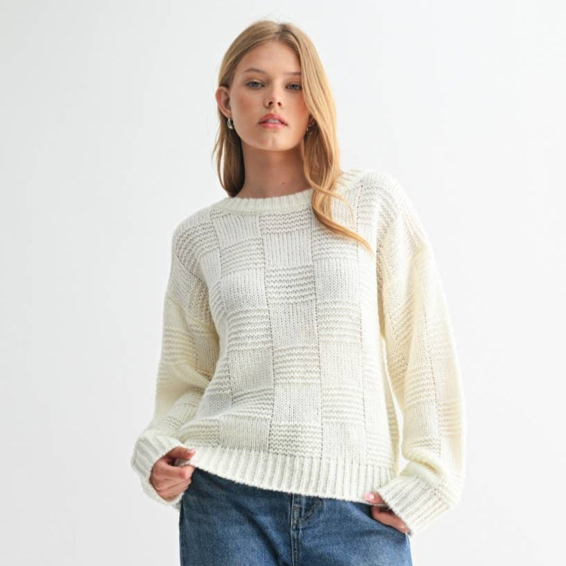 Woman wearing a cream sweater and blue jeans on a white background