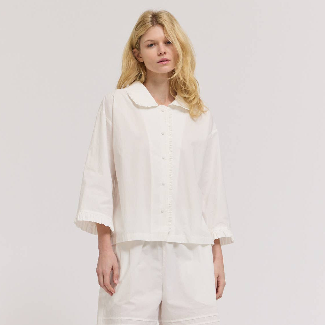 Woman wearing a white outfit with a plain background
