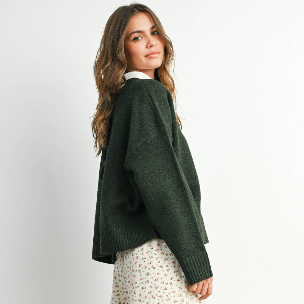 
                      
                        Woman wearing a green sweater and patterned pants on a white background
                      
                    