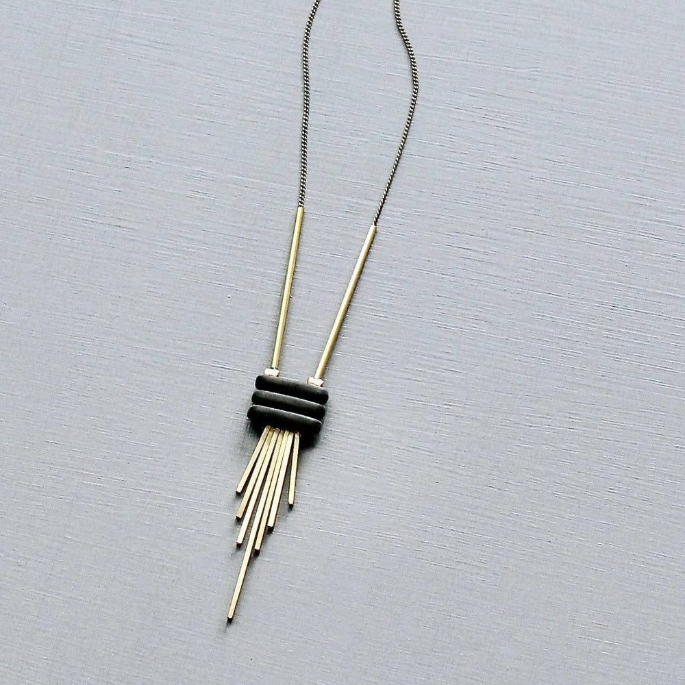 Necklace with a black and gold pendant on a gray background