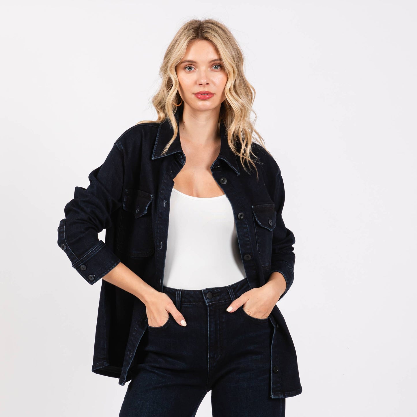 Woman wearing a black jacket and pants with a white top on a white background