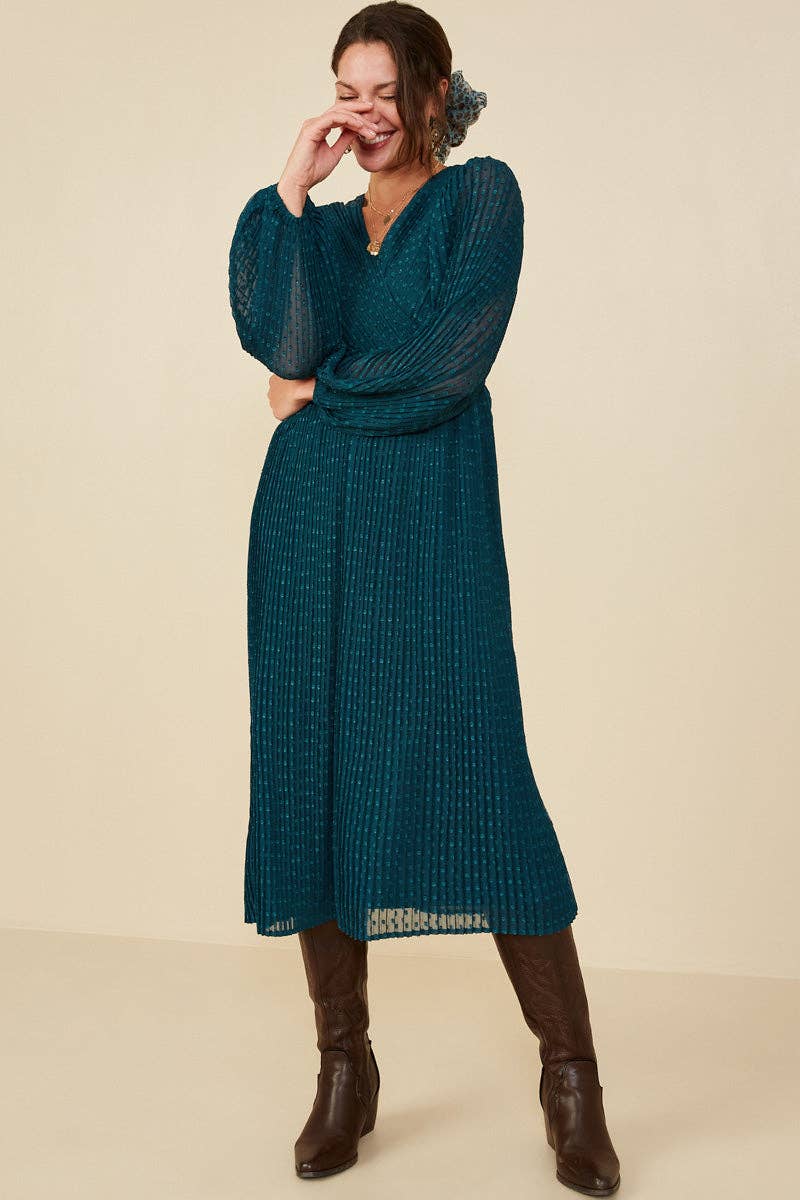 Woman wearing a teal dress with long sleeves and a matching headband against a beige background