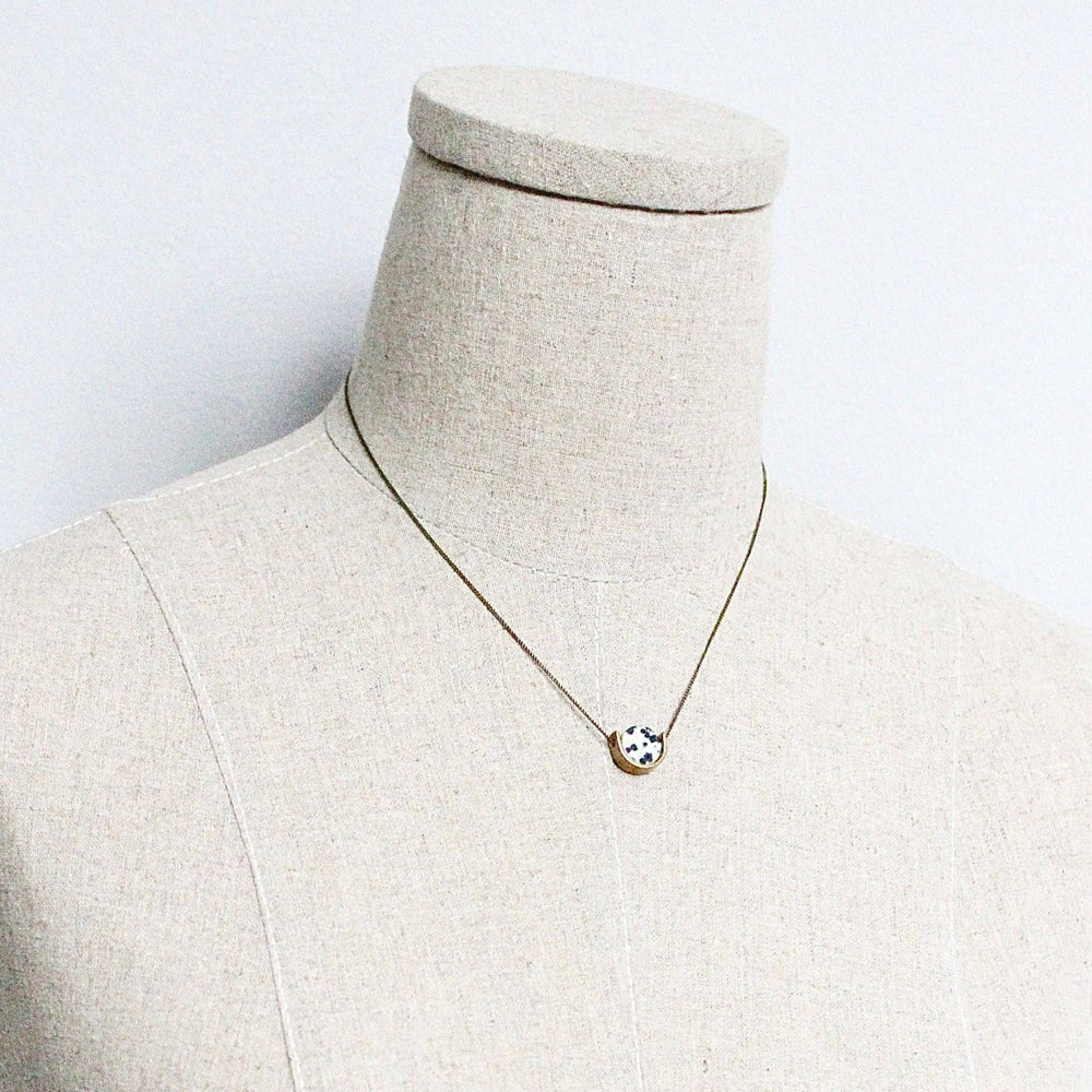 Necklace with a small round pendant on a mannequin against a white background