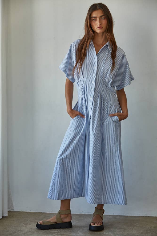 Woman wearing a light blue striped dress against a plain background