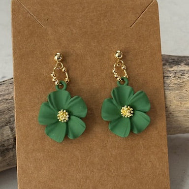 Green flower earrings on a brown card with a gray background