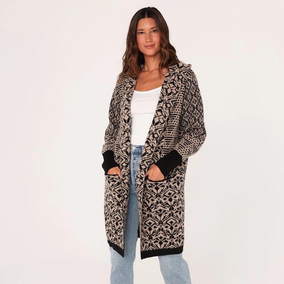 
                      
                        Woman wearing a patterned cardigan, white top, and jeans on a white background
                      
                    